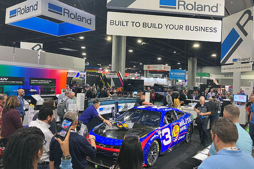 People watching the live vehicle wrap demonstration at PRINTING United Expo