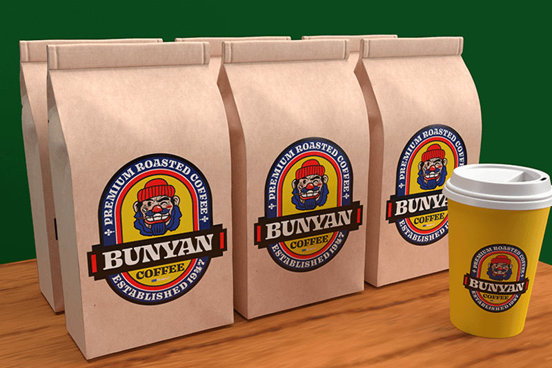 Seis bolsas de papel marrón con etiquetas “Bunyan Coffee” y un vaso de café desechable con la misma etiqueta.