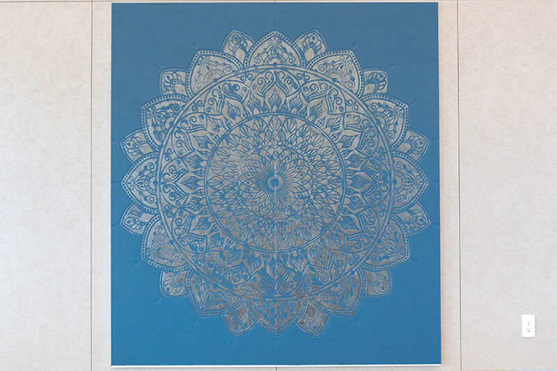 Diseño circular impreso sobre fondo azul, enmarcado y colgado.
