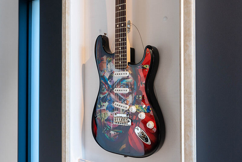 Colorida guitarra eléctrica con atractivos gráficos, colgada en una pared del área de exhibición de Roland DG.