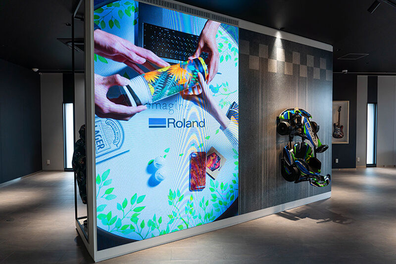 A wall with colorful graphics and a go cart with vehicle graphics in the Roland DG headquarters exhibition space