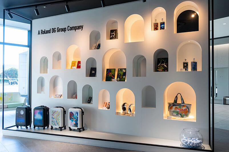 Una pared de presentación en el área de exhibición de Roland DG mostrando productos creados con dispositivos Roland DG.