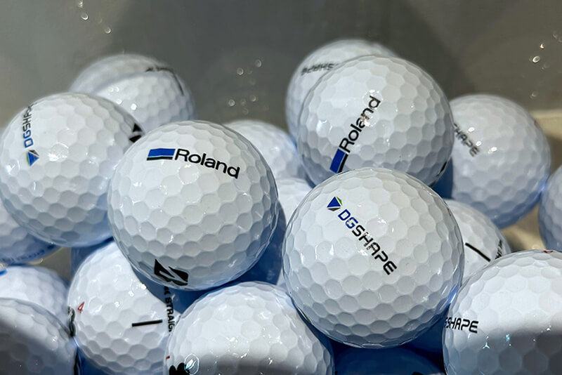 A group of golfballs printed with the Roland DG logo.
