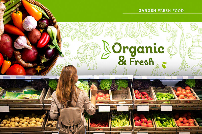 Woman examining fresh produce with wall graphics above saying "organic & fresh"