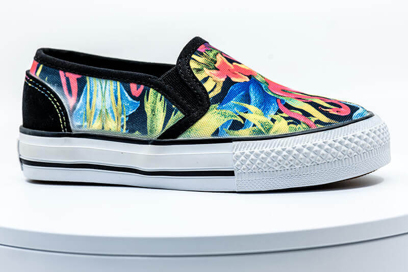 Slip-on canvas shoe with colorful graphics on the canvas portions.