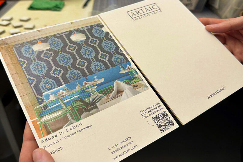 Hands holding a sample board with a proposed mosaic design.