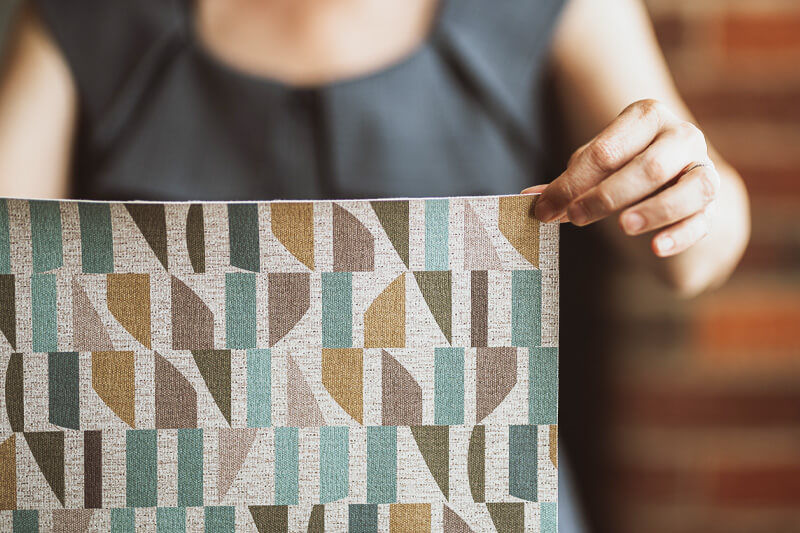 Woman holding large pattern square in front of her.