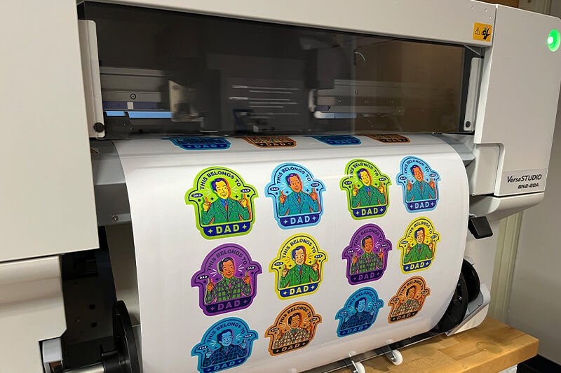 Vista de stickers siendo impresos con la impresora/cortadora VersaSTUDIO<sup>®</sup> BN2-20 de Roland DG.