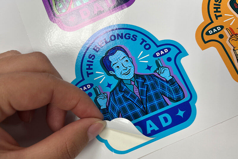 Hand peeling "This Belongs to Dad" sticker.