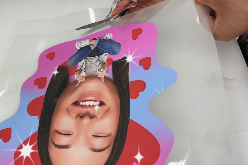 Hands using scissors to cut excess material away from the design.