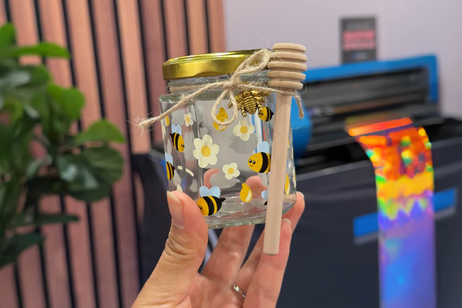 Hand holding clear jar with decals of bees.