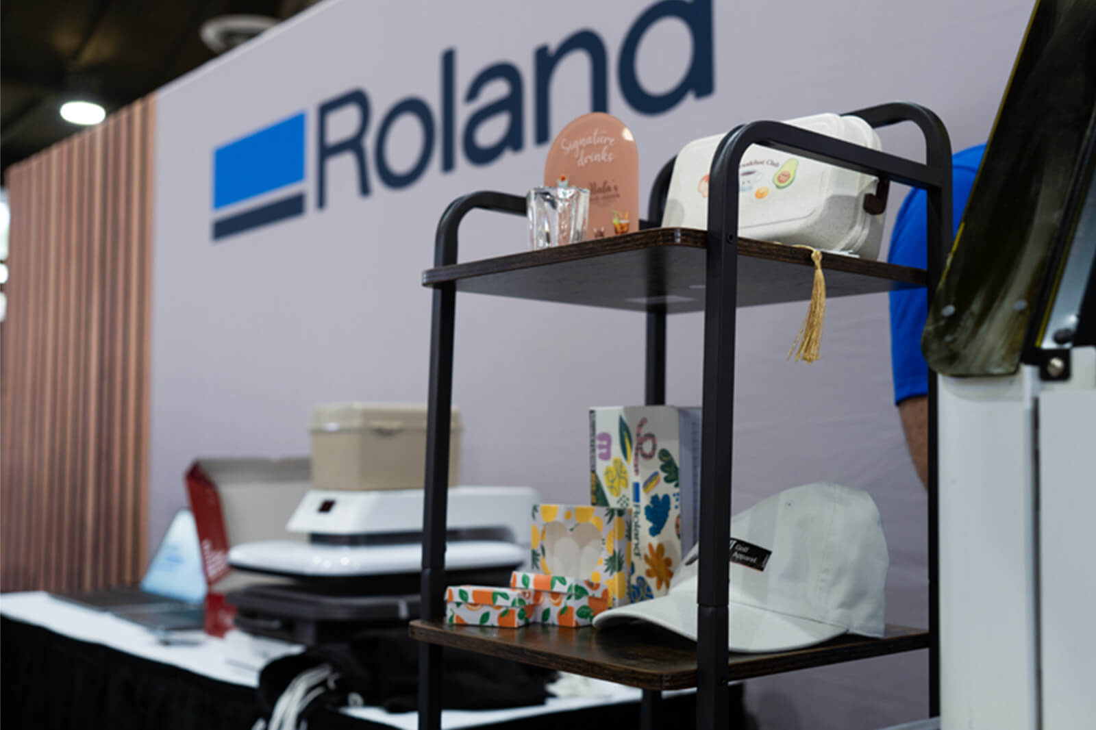 View of back wall of Roland booth with equipment, logo sign and samples.