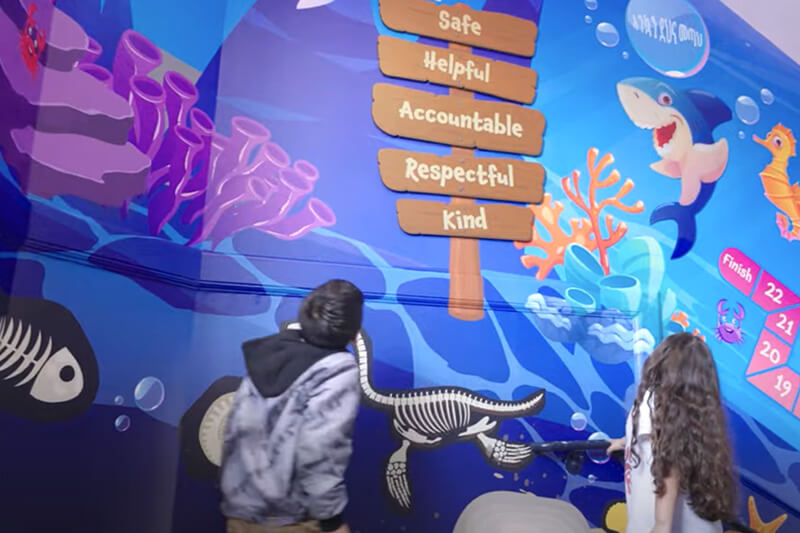 Escolares viendo los coloridos gráficos, impresos digitalmente, en las paredes de la escalera.