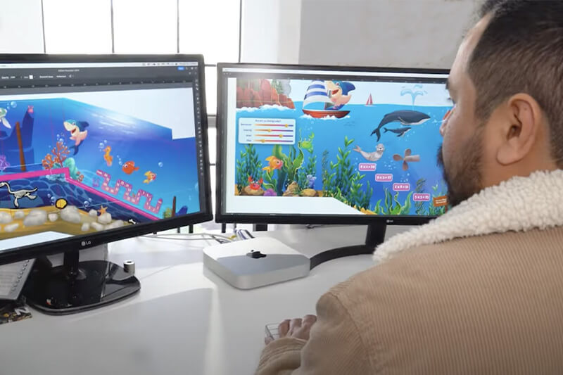 Técnico trabajando en posicionar los coloridos gráficos en dos pantallas de computadora antes de su impresión.