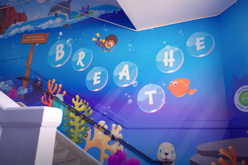 Gráfico con burbujas que deletrean la palabra “Breathe” (“respira”) en la pared de la escalera.