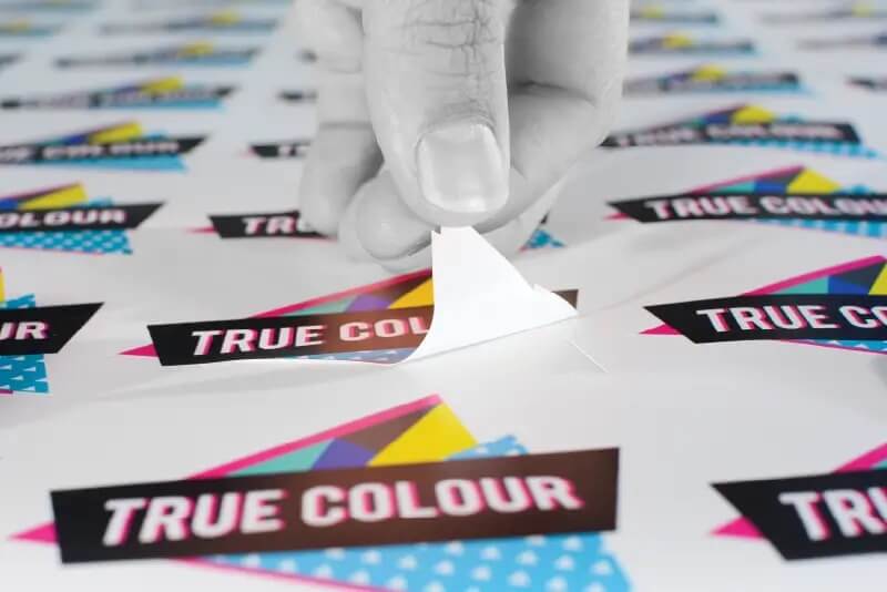 Mano escardando una lámina de stickers.