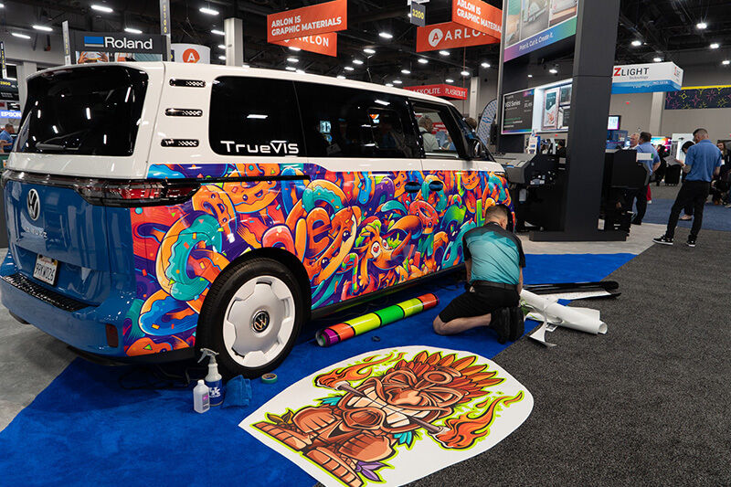Close up side and rear view of wrapped VW electric bus at Roland DGA booth at ISA.