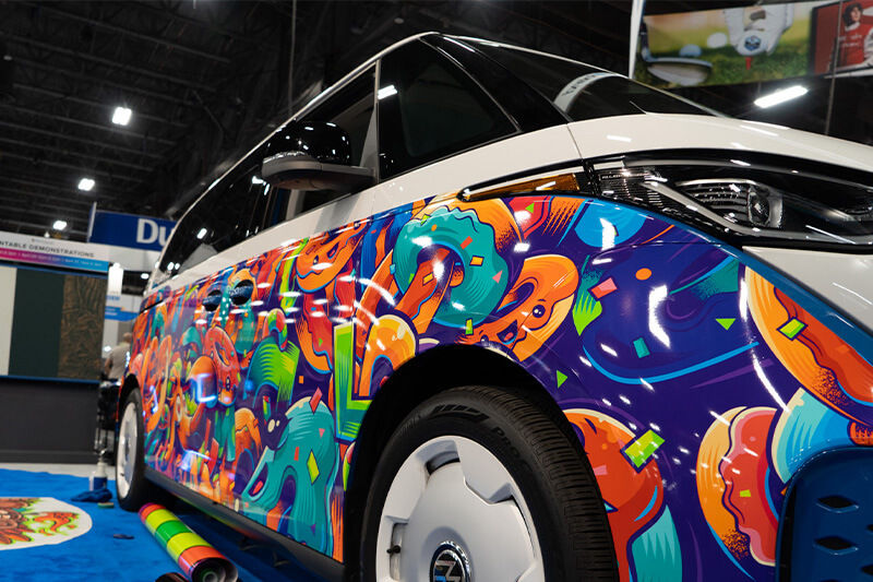 Close up front fender view of wrapped VW electric bus at Roland DGA booth at ISA.
