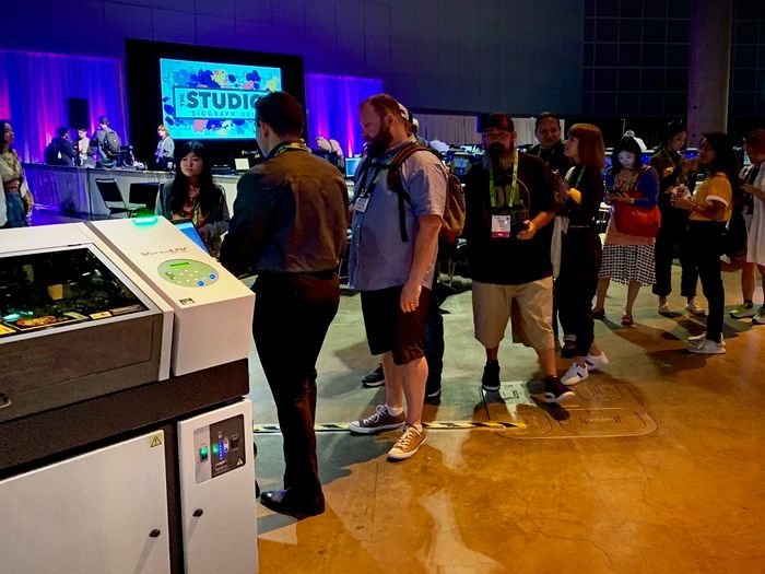 Los asistentes a SIGGRAPH 2019 interactúan con las avanzadas impresoras UV y Directo-a-Prenda de Roland DG.