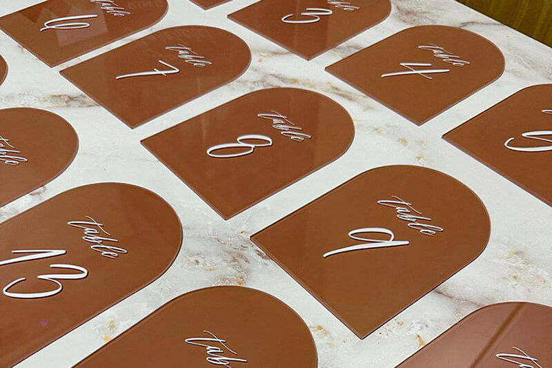 White background with brown arch shaped table number signs for a wedding.