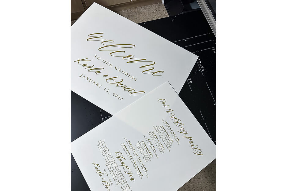Two white cards with "Welcome to our wedding" and ceremony details printed in gold lettering.
