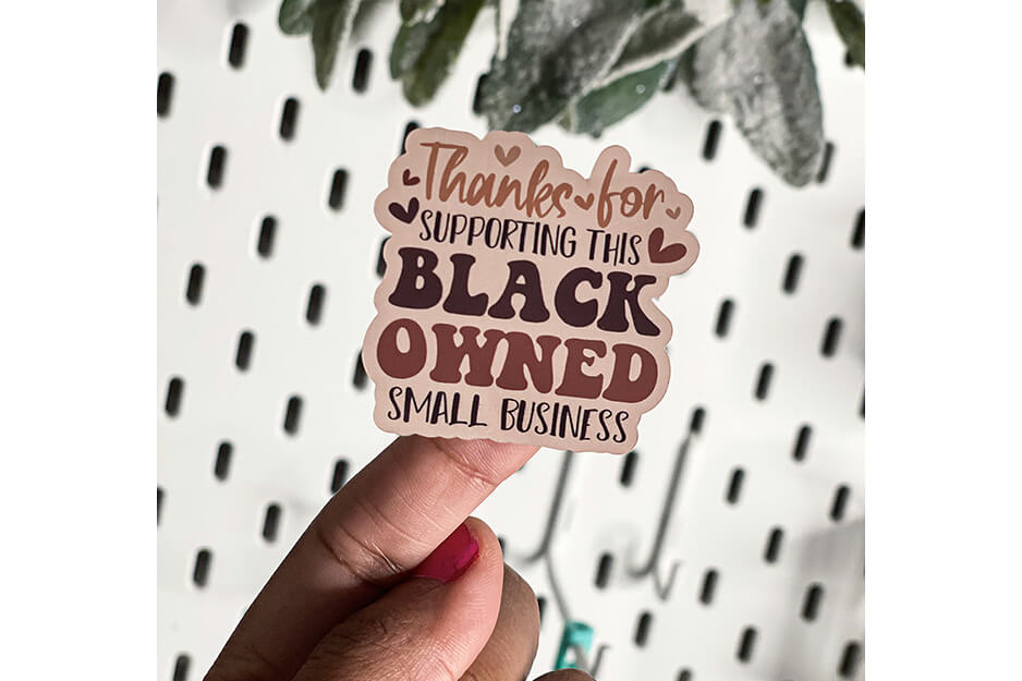 Finger holding sticker that says "Thank you for supporting a black owned small business"