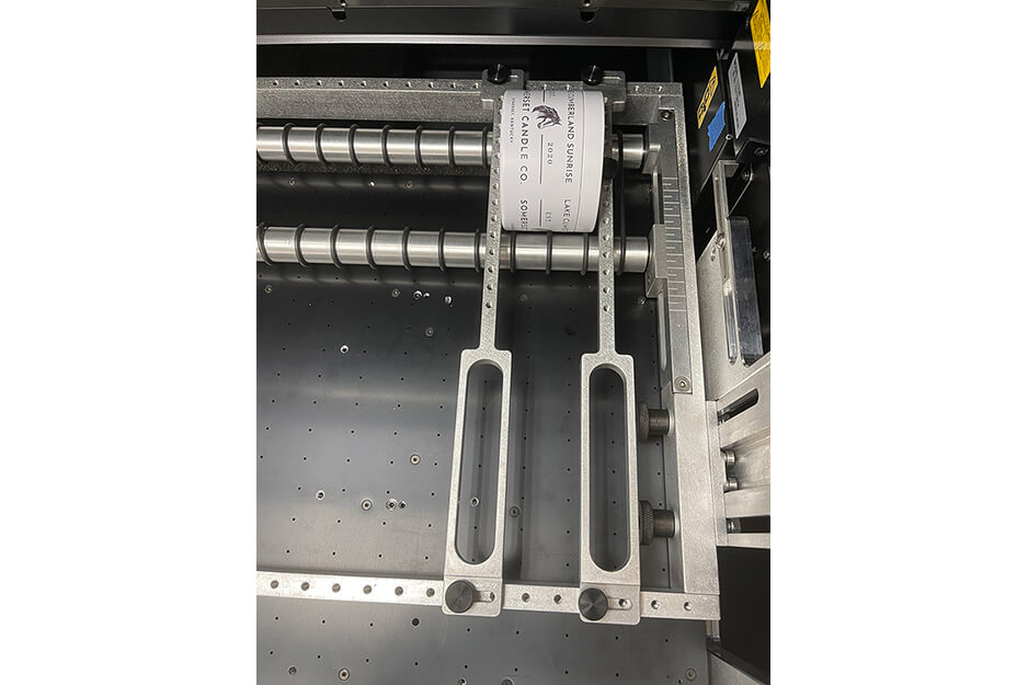 Pillar candle being held by Roland DG Rotary Rack attachment after label printing on a Roland DG LEF2-300D UV benchtop flatbed printer