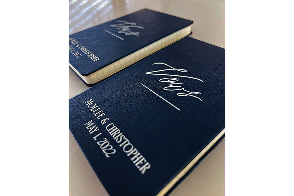 Two navy notebooks with "Vows" and "Mollee and Christoper May 1 2022" printed on them