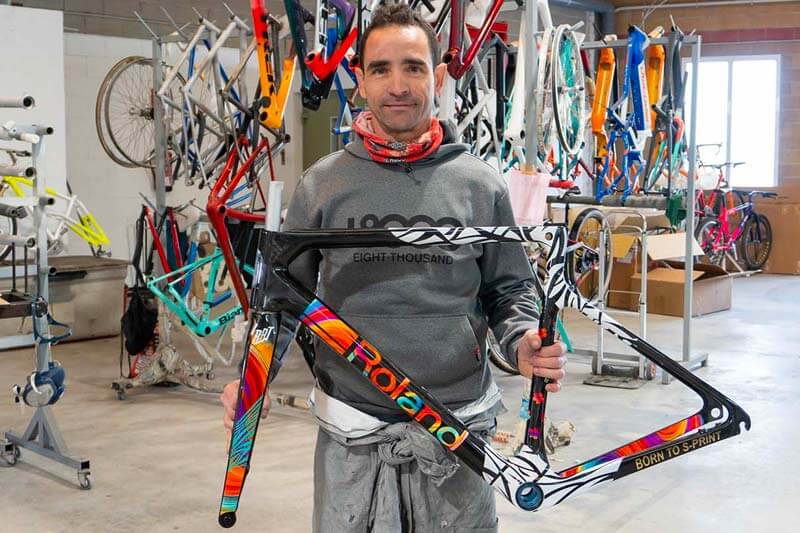 Sergio Vergel Escribano, propietario del taller SColors, mostrando un colorido cuadro de bicicleta personalizado
