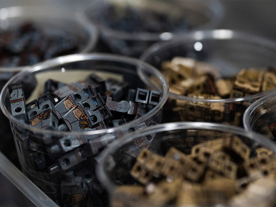 Mini figure pieces in round cups awaiting customization.