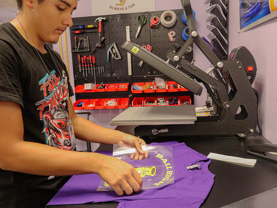 Ball HS Tor_Slider Image_Tor Store student applies a transfer to a t-shirt.