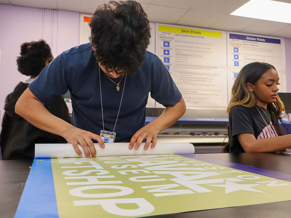 Ball HS Tor_Slider Image_Tor Store student rolls a printed banner