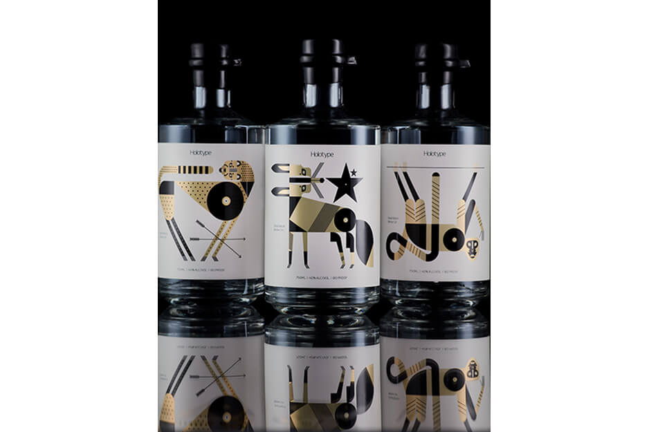 Three dark bottles with white labels and colorful graphics printed on a Roland DG UV printer.