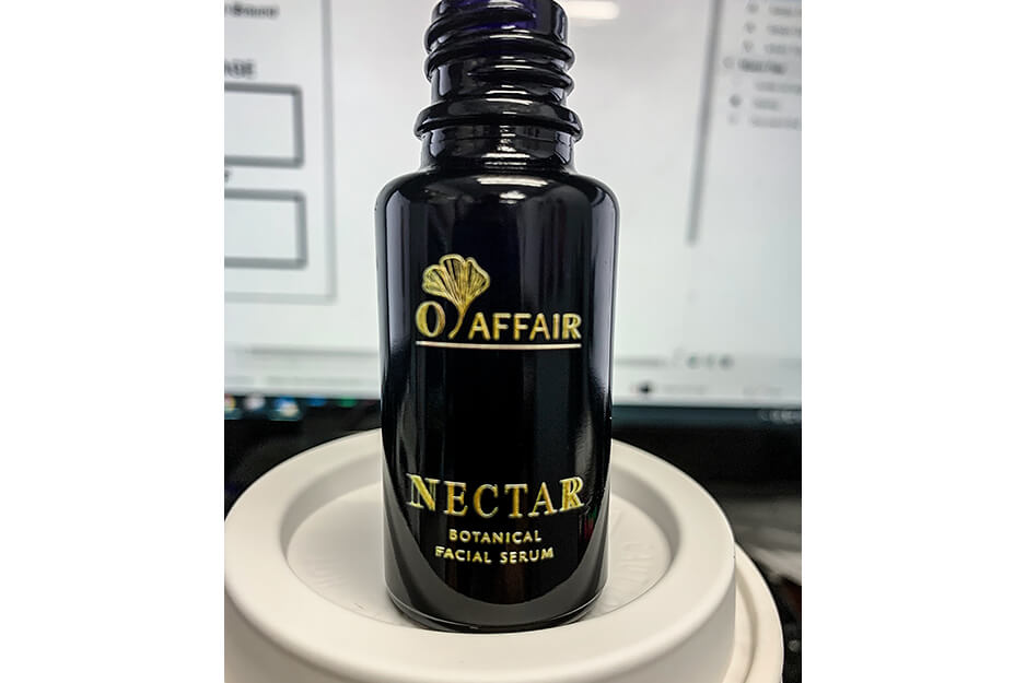 Close up of small brown bottle with gold lettered words "O Affair Nectar Botanical Facial Serum"