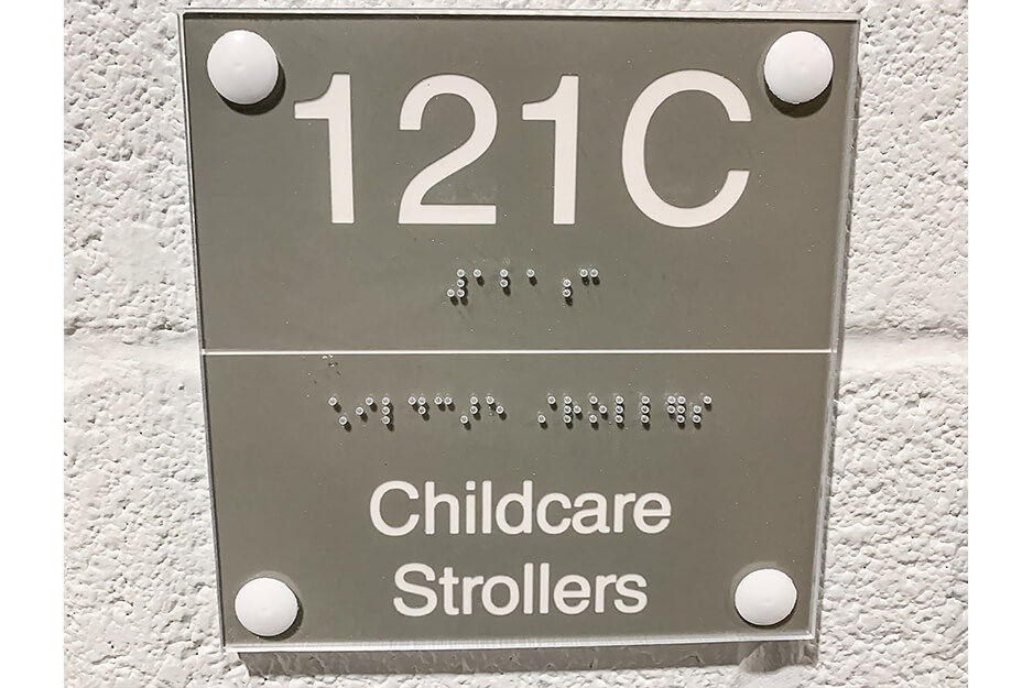 Wayfinding signage with Braille and the words "121C Childcare Strollers"