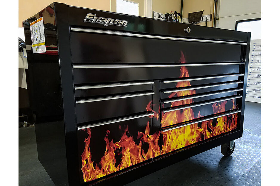 A black tool box is wrapped in graphics depicting fires, printed on a Roland DG TrueVIS VG2 printer/cutter.