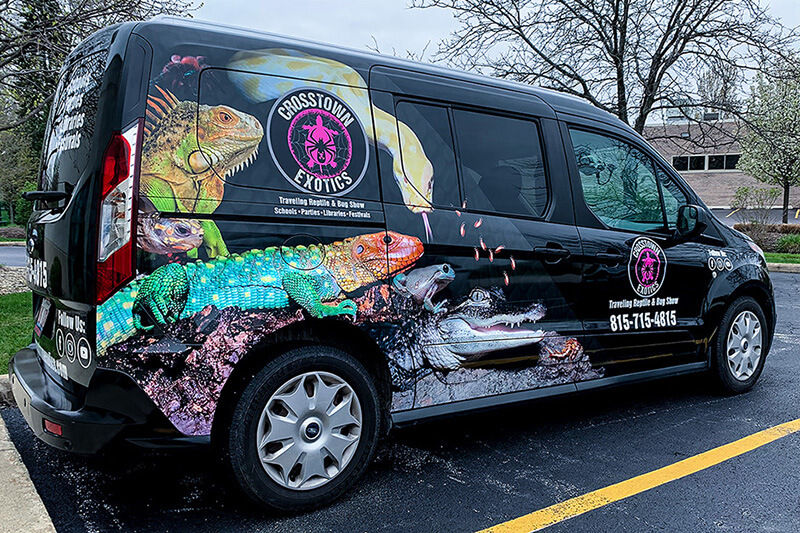 Black van with colorful graphics and words "Crosstown Exotics Traveling Reptile and Bug Show"