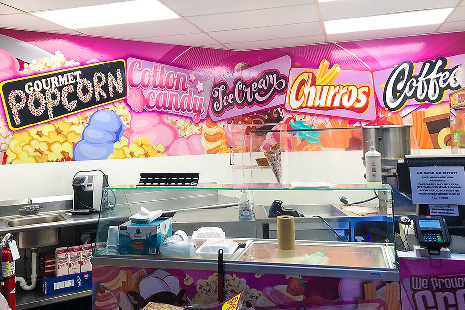 Food hall with colorful wall mural graphics and text for popcorn, churros, and coffee