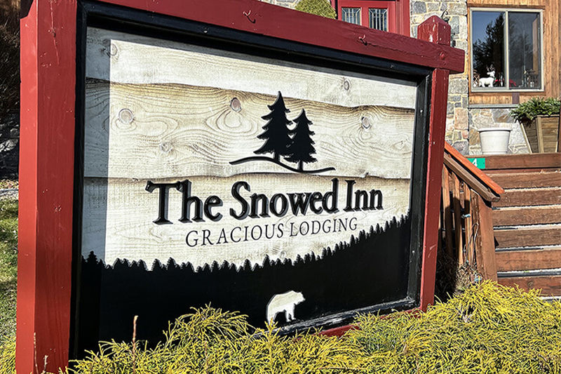 Letrero de exteriores con la frase “The Snowed Inn” y gráficos de pinos hechos con la impresora/cortadora eco-solvente TrueVIS™ VG de Roland DG.