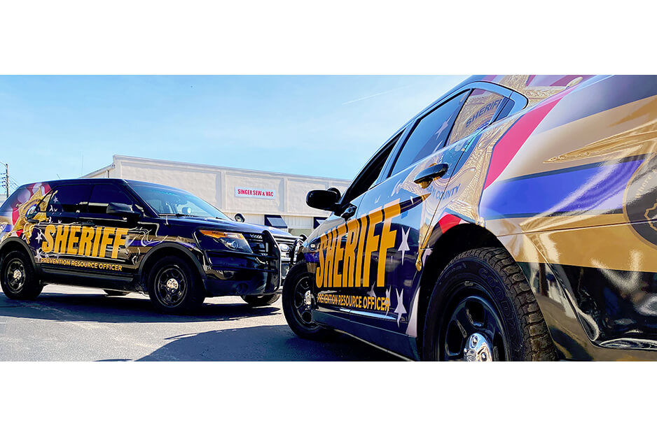 Two sheriff's department vehicles with vibrant graphics printed by J Signs & Graphics on their Roland DG TrueVIS VG2 wide-format printer/cutter.