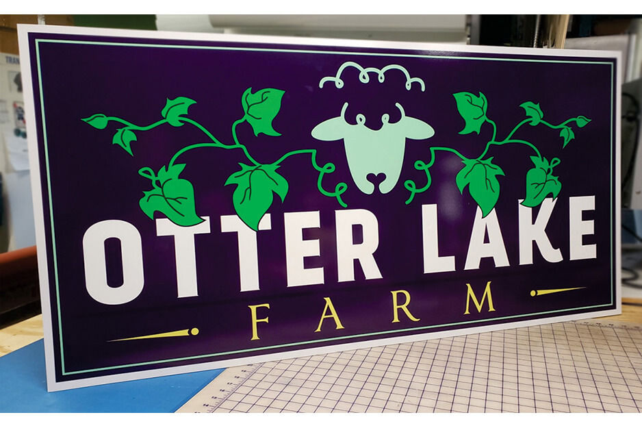 Rectangular sign for Otter Lake Farms on table.