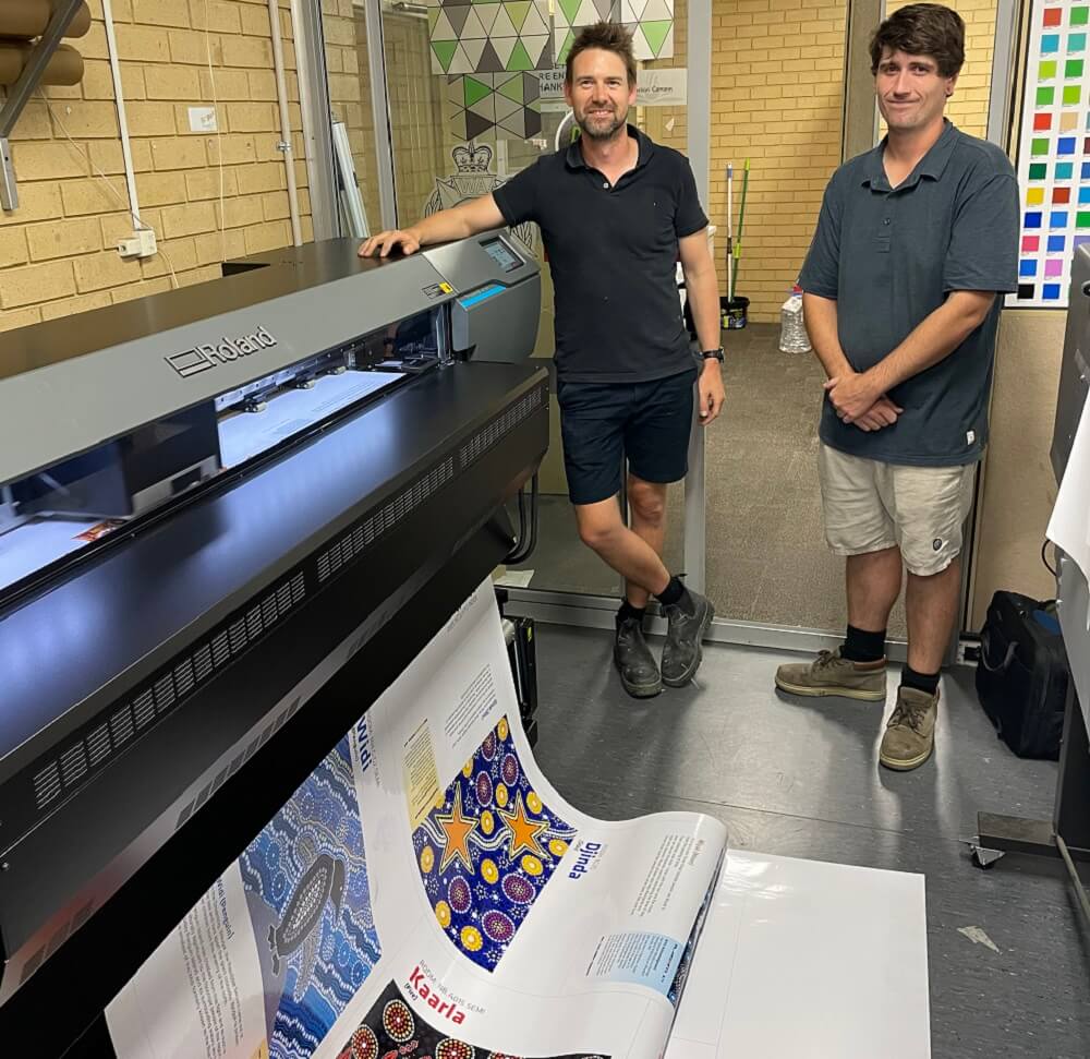 Poolegrave Signs and Engraving employees stand next to their Roland DG TrueVIS AP-640 resin printer.
