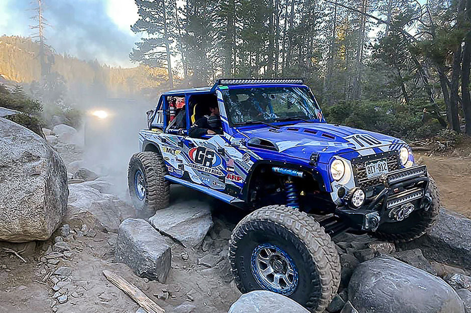 All terrain Jeep with blue graphics traversing rocks.