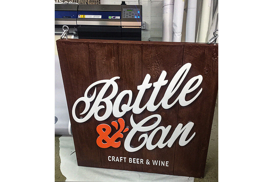 Brown sign with white and red graphics reading "Bottle & Can" produced on a Roland DG TrueVIS VG2 printer/cutter