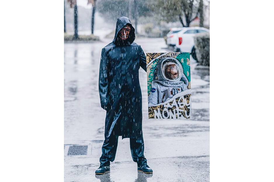 Man in the rain wearing a facemask holds blue poster-sized sign