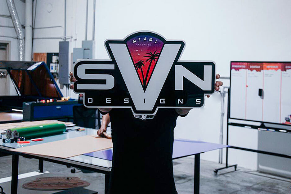 Hombre sujetando el logotipo de SVN Designs frente a su cara.