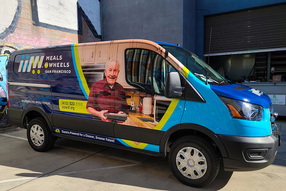 Camioneta Meals on Wheels con coloridos gráficos mostrando un cliente adulto mayor