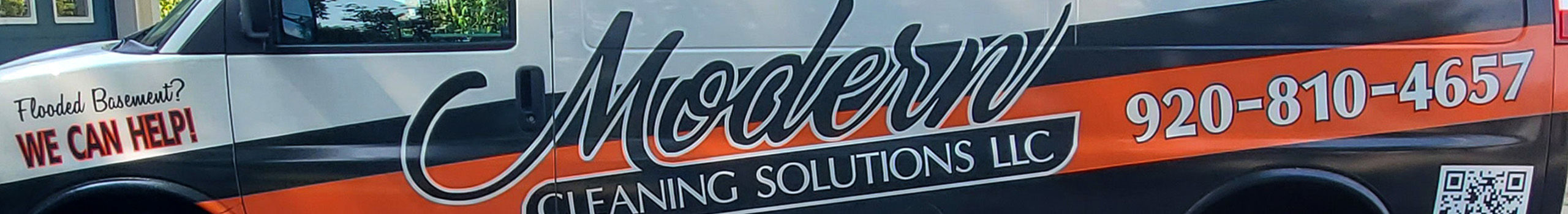 Side view of a van with black, orange and white vehicle wrap.
