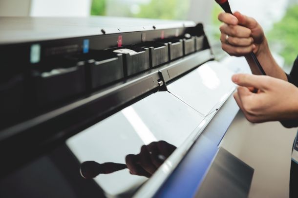Roland DGA technician servicing a TrueVIS printer under warranty